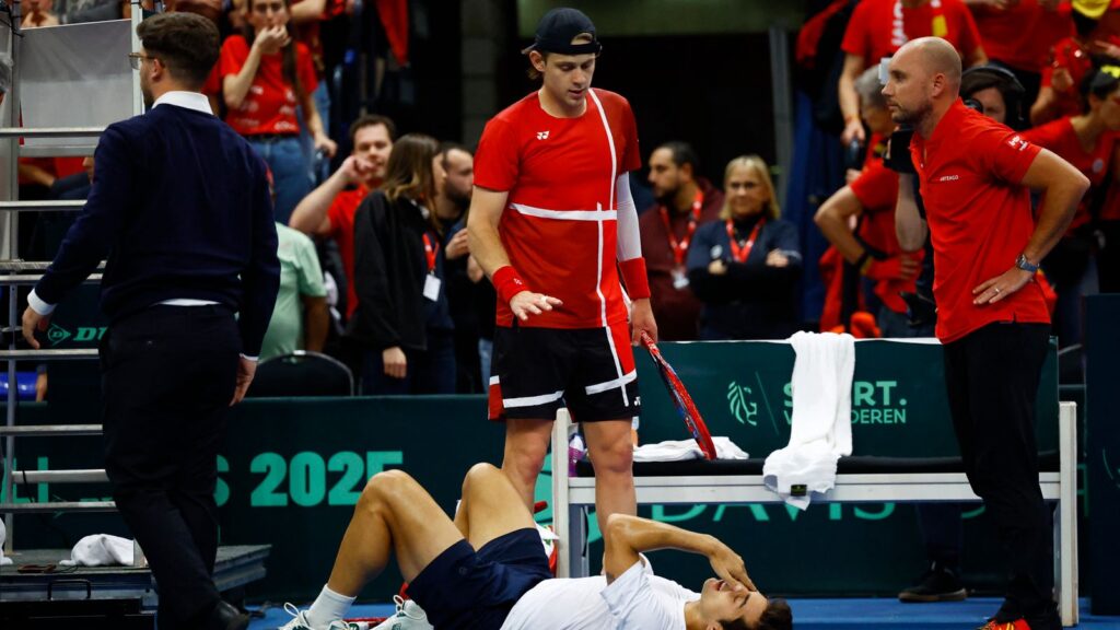 Chile's Cristian Garin laid on his back after the collision as Zizou Bergs stands directly over him. Pic: Reuters